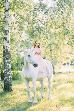 Bir at ile ormanda gün batımında hava fotoğraf çekimi. Tek boynuzlu atlı uçan elbiseli bir kız..