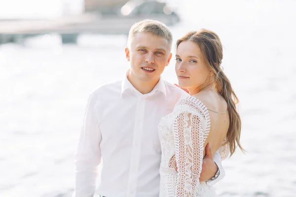 一对年轻的新婚夫妇在水边的码头上 日落时的婚礼照片拍摄 — 图库照片