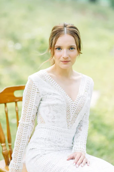 The bride in a wedding dress in nature with a bouquet. Boudoir photo shoot in pine lemu in the style of fine art.