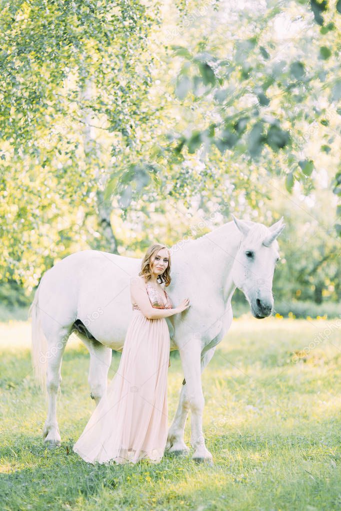 Aerial photo shoot at sunset in the forest with a horse. A girl in a flying dress with a unicorn.