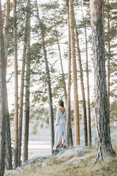松林の中の私室のドレスの少女 薄いドレスを飛んでの岩の上に立っています 結婚式で 自然と団結 夕暮れ時の花嫁 — ストック写真