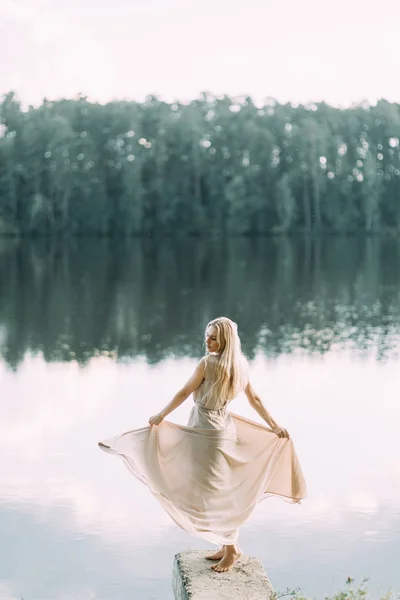 日落时穿着闺房礼服的女孩在湖边 费用新娘的性质 美丽的模型 长头发的俄罗斯女孩 — 图库照片