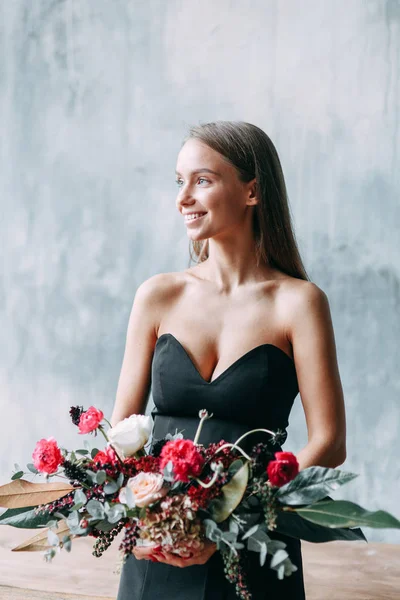 Stylish bride in a black dress in the Studio. Flower arrangement and bouquet, the girl on the table.