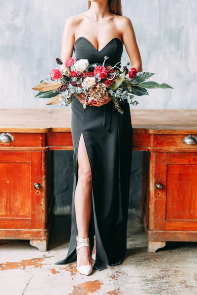Stylish bride in a black dress in the Studio. Flower arrangement and bouquet, the girl on the table.