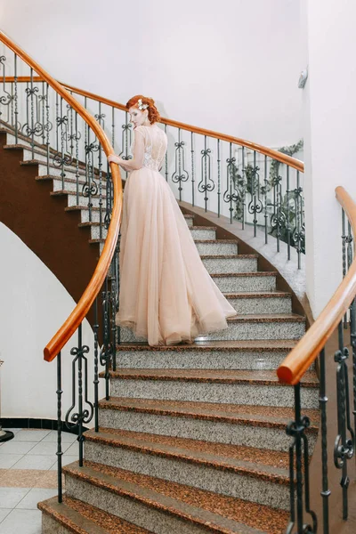 The bride is in an expensive hotel on the stairs. Wedding photo shoot in a beautiful dress.