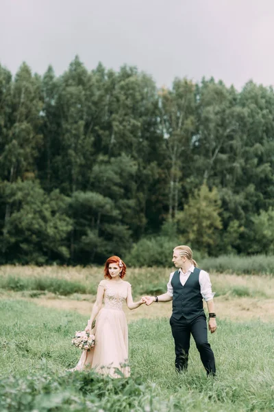 フィールドで自然の中の結婚式 草の上歩く新郎新婦 — ストック写真