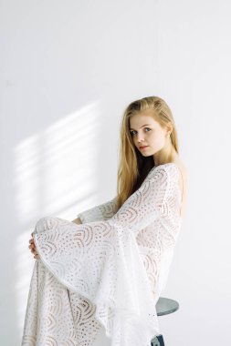 Güzel gelin beyaz Studio bir sandalyede oturuyor. Minimalist Avrupa tarzında düğün.