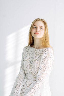 Güzel gelin beyaz Studio bir sandalyede oturuyor. Minimalist Avrupa tarzında düğün.