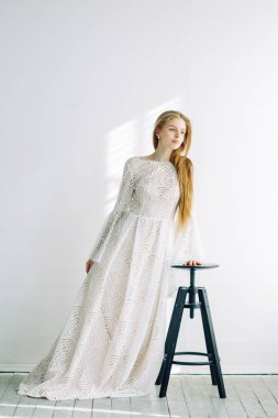 Güzel gelin beyaz Studio bir sandalyede oturuyor. Minimalist Avrupa tarzında düğün.