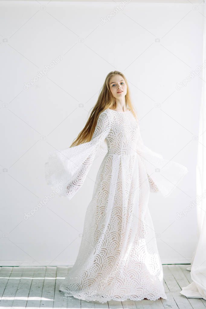 Beautiful bride on a white minimalistic background. Wedding preparations in fine art.