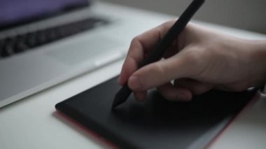 Sanatçının grafik tableti üzerinde çizim. Makro düğmesi ile elin yakın bir görünümü.