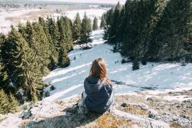 Kış seyahat ve doğa. Genç bir Blogger oturur ve güzel bir görünüm ile bir dağın üzerinde duruyor. 