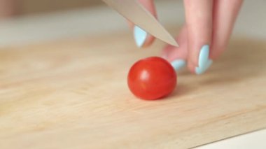 Salata için çeri domates dilimleme. Ahşap bir tahta üzerinde domates kesme.