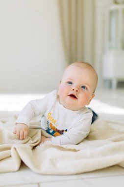 Fotoğraf stüdyosunda açık arka planda bir çocuk. Annesinin kollarında bebek. 