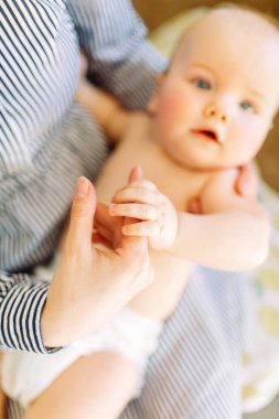 Fotoğraf stüdyosunda açık arka planda bir çocuk. Annesinin kollarında bebek. 