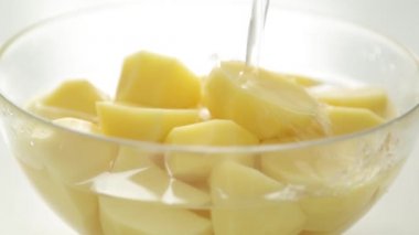 Soyulmuş patatesleri yıkayarak suya dalmak. Bir yemek blogu için pişirme.