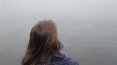 Göl manzaralı iskelede oturan kız. Seyahat blogger doğahayran.