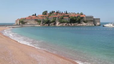 Sveti Stefan adası yakınında pitoresk sahil. Karadağ'da kum ve şezlonglu turistik plaj.
