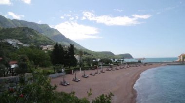 Sveti Stefan adası yakınında pitoresk sahil. Karadağ'da kum ve şezlonglu turistik plaj.