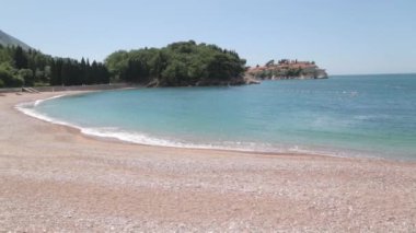 Sveti Stefan adası yakınında pitoresk sahil. Karadağ'da kum ve şezlonglu turistik plaj.