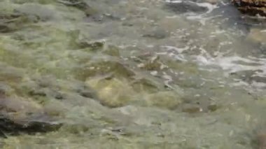 Yukarıda dalgalar ve deniz suyu dokusu. Taş sahildeki mavi su ve dokulu köpük.