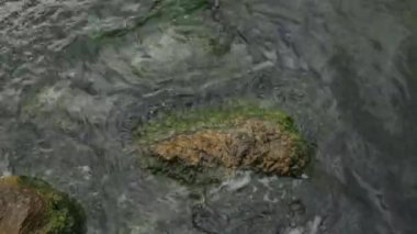 Yukarıda dalgalar ve deniz suyu dokusu. Taş sahildeki mavi su ve dokulu köpük.