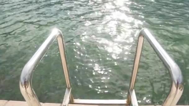 海岸近くの海水に太陽がにらみつく モンテネグロの水を出るために桟橋とスチールハンドル — ストック動画
