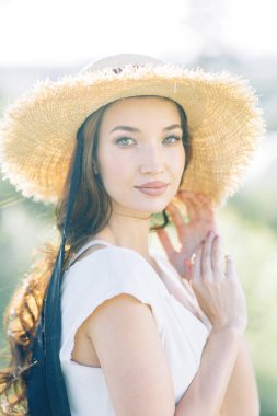  Beyaz elbiseli ve şapkalı güzel bir kız. Gün batımında Parkta Yaz fotoğraf çekimi.