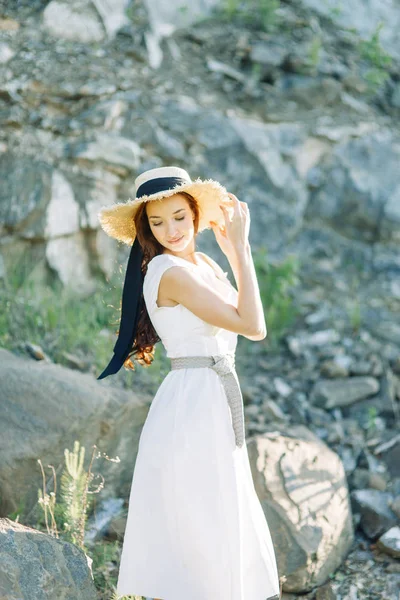 岩や石で公園で夏の写真撮影 白いドレスと帽子の美しい女の子 — ストック写真