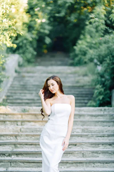 岩や石で公園で夏の写真撮影 白いドレスと帽子の美しい女の子 — ストック写真