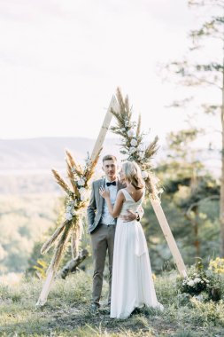 Gün batımında şık bir çift. Üçgen kemerli düğün töreni. 