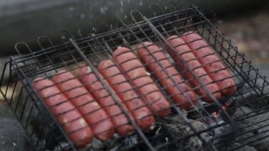Izgara barbeküde kızarmış sosis. Ateş ve duman ile doğada piknik.