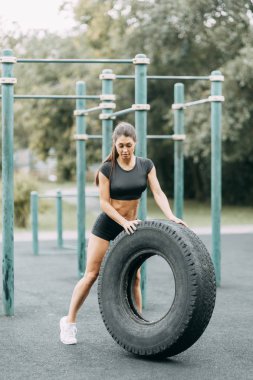 Eğitim ve bir lastik ile poz. Oyun alanında güzel atletik kız. 