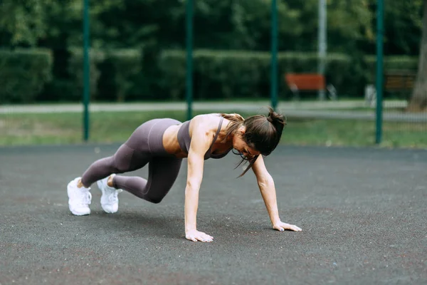 Push-UPS, workout and plank on the street. Beautiful athletic girl on the Playground. Push-UPS, workout and plank on the street.