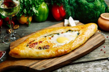 Ahşap arka planda sebze dekoru olan Azerbaycan restoranı yemeği. Kurulda Adjarian 'daki Khachapuri. 