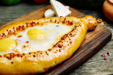 Ahşap arka planda sebze dekoru olan Azerbaycan restoranı yemeği. Kurulda Adjarian 'daki Khachapuri. 