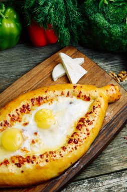 Ahşap arka planda sebze dekoru olan Azerbaycan restoranı yemeği. Kurulda Adjarian 'daki Khachapuri. 