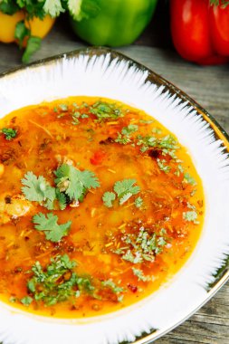 Ahşap arka planda sebze dekoru olan Azerbaycan restoranı yemeği. Bitkilerle dolu kilden bir tencerede çorba.. 