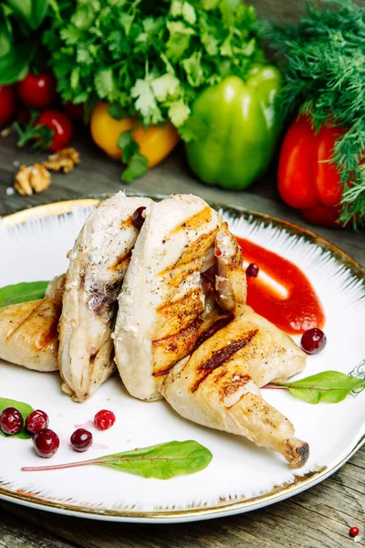 Ahşap arka planda sebze dekoru olan restoran yemeği. Soslu tütün tavuğu ve tabakta otlar.. 