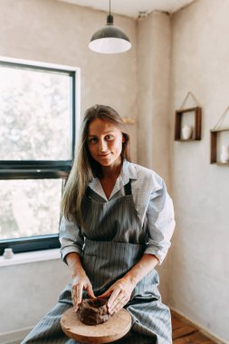 Güzel, ilham verici seksi, kot pantolonlu, gömlekli, atölyede çalışan çömlekçi çarklı, el yapımı yaratıcılık sanatçısı kadın iş yerinde, hobisi, boyalı ve kille boyanmış kız.