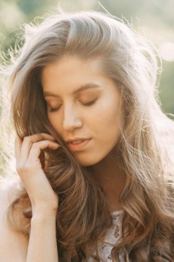 Sağlıklı bir cilde ve yeşil bir bitkiye sahip bir kadın yüzü. Gün batımında kadın portresi.