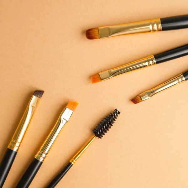 Set of gold and black brow brushes concept. Makeup artists brushes on an isolated background.