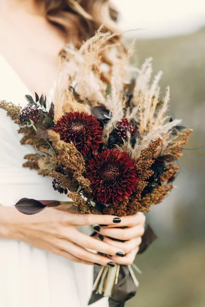 Wedding bouquet in boho style on the background of nature. The bride holds a bouquet of dried flowers. — Stock Photo, Image