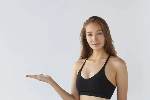 Porträtt av en ung kvinnlig idrottsman på en vit bakgrund, pekar. Träna idrott motivation begreppet livsstil. — Stockfoto