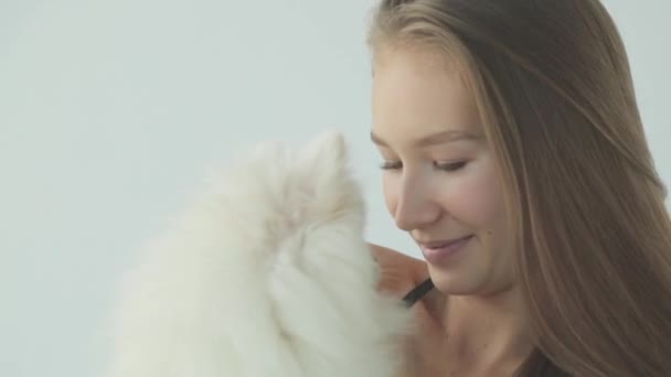 Ένα σπορ κορίτσι προπονείται στο γυμναστήριο με ένα σκύλο. Πορτρέτο ενός κοριτσιού με ένα μικρό σκυλί, χαμογελώντας και γελώντας. — Αρχείο Βίντεο