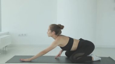 Ayakta yoga yaparken bacaklarını esneten genç bir kadın spor ya da aktif yaşam tarzının bir parçası olarak esneme hareketleri yapıyor. Sporcu kız antrenmandan önce ısınır..