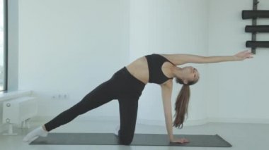 Ayakta yoga yaparken bacaklarını esneten genç bir kadın spor ya da aktif yaşam tarzının bir parçası olarak esneme hareketleri yapıyor. Sporcu kız antrenmandan önce ısınır..