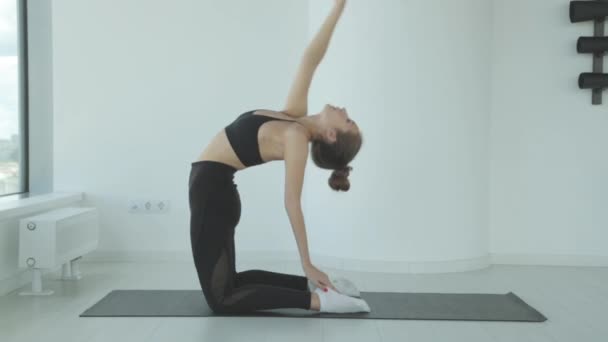 Una mujer joven que estira las piernas en ejercicios de yoga de pie que se estiran como parte de un trabajo de fitness o estilo de vida activo. Chica de fitness hace el calentamiento antes del entrenamiento. — Vídeos de Stock