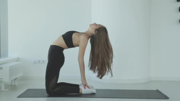 Una mujer joven que estira las piernas en ejercicios de yoga de pie que se estiran como parte de un trabajo de fitness o estilo de vida activo. Chica de fitness hace el calentamiento antes del entrenamiento. — Vídeos de Stock