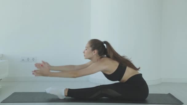 Eine junge Frau, die im Stehen ihre Beine streckt, übt Stretching als Teil eines Fitnessjobs oder aktiven Lebensstils. Fitness-Mädchen macht Aufwärmtraining vor dem Training. — Stockvideo